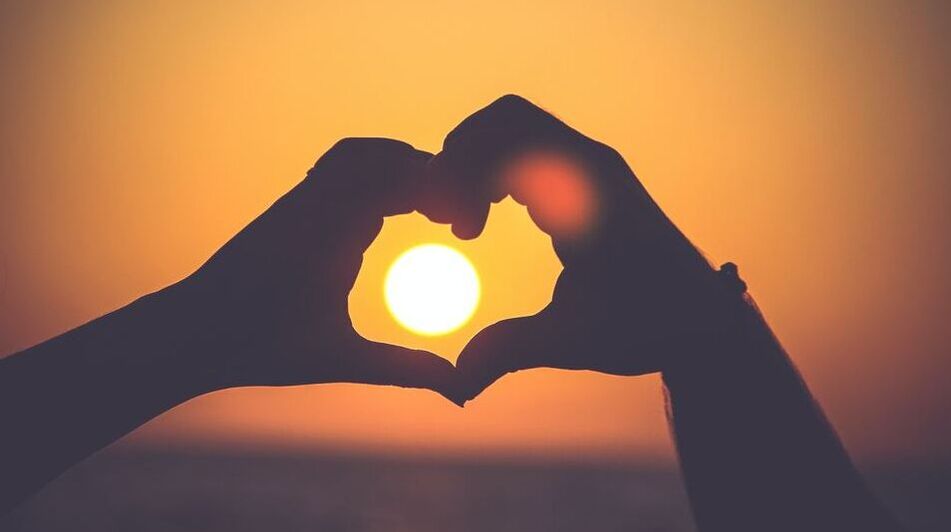 Picture A couple's hands held in the shape of a heart framing a setting sun | Hillmac Electrical and Solar Colab | Image by mayur-gala-2PODhmrvLik-unsplash